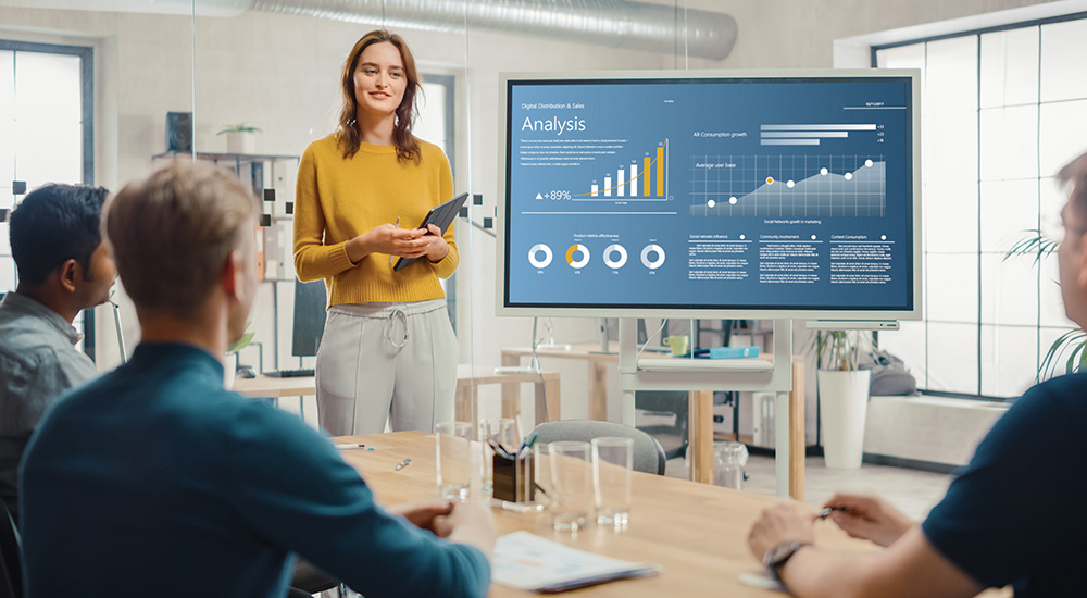 young woman giving a presentation using a large display with a detailed information graphic