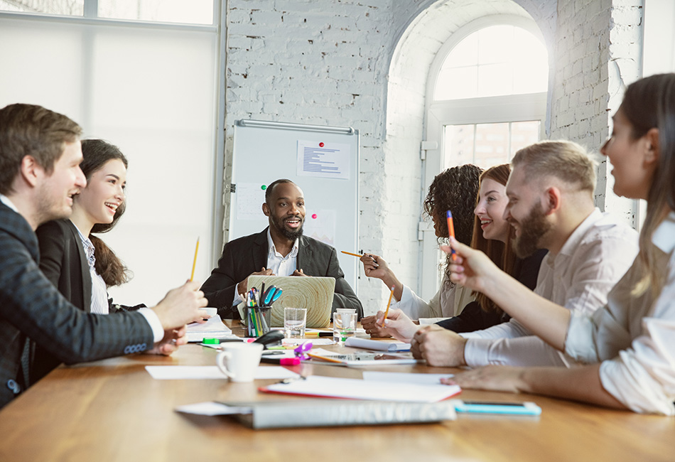 A diverse group of employees discussing at a meeting table with documents