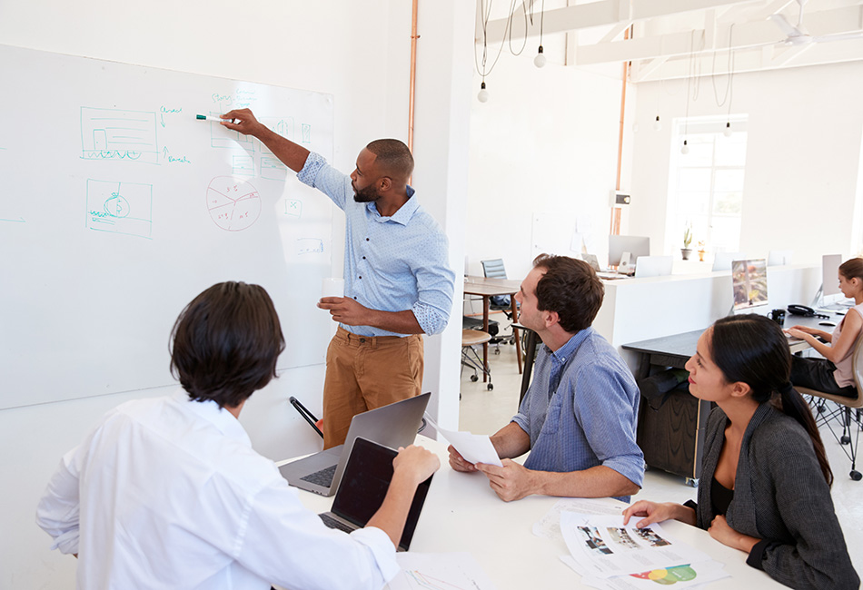 A diverse group of employees working on concepts at a whiteboard